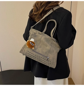 Macro shot of retro grey tote bag with metal rivets, side tassels and plush doll charm