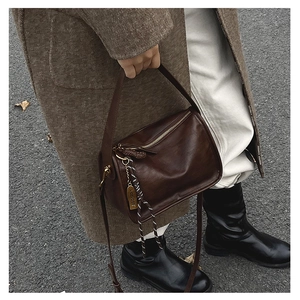 Détails de ce sac seau en cuir marron foncé avec texture rétro et finitions en métal doré