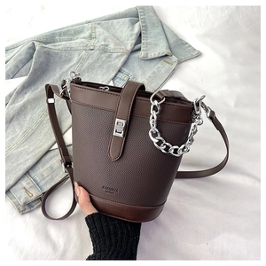 Detail of coffee bucket bag with lychee texture leather and silver chain strap