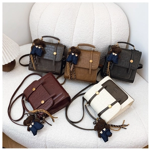 Detail of stylish crocodile pattern embossed mini backpacks with cute bear charms