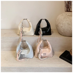 Détail de quatre sacs à main colorés avec poignées en métal argenté sur pierre
