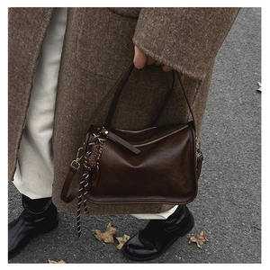 Gros plan du sac rétro en cuir PU marron foncé avec breloque décorative en sangle tissée