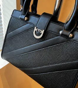 Détail d'un sac à main en cuir noir avec boucle fer à cheval en strass et poignée