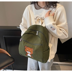 Close-up of forest green corduroy backpack featuring a cute brown bear embroidery