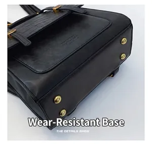 Detail of black crossbody bag featuring gold-tone protective feet and crocodile pattern