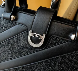 Gros plan d'une boucle en fer à cheval avec strass blancs sur un sac en cuir noir grainé