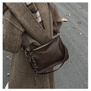 Détail d'un sac bandoulière marron foncé vintage avec nœud tressé sur manteau d'automne