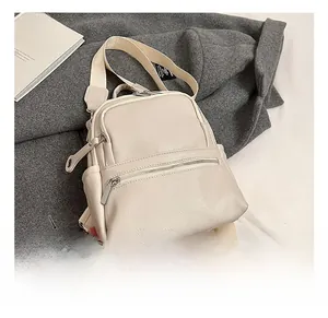 Detailed close-up of beige litchi grain faux leather backpack with multiple zip pockets
