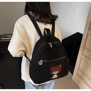Detail of black corduroy backpack with cute bear embroidery and decorative zipper charm