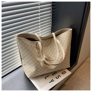 Close-up of beige monogram tote bag featuring a cute bear charm on a minimalist windowsill