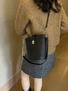 Minimalist black pebble leather bucket bag with silver chain strap shown on model