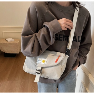 Detail der cremefarbenen Kuriertasche mit Nylonstruktur und verstellbarem Gurtband