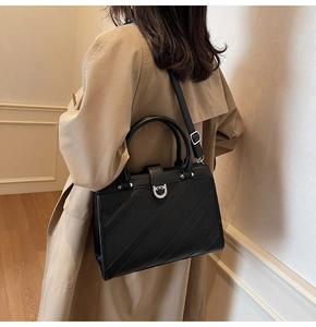 Dettaglio borsa nera in pelle con fibbia a ferro di cavallo su trench color kaki scuro