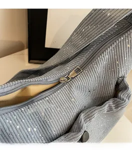 Detail of smooth metal zipper on grey corduroy crossbody bag with silver sequins