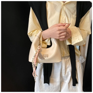 Détail du sac hobo montrant le fini en cuir PU brillant et le pompon tissé élégant