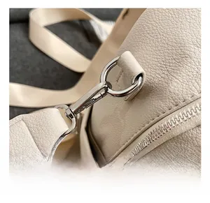 Close-up of beige lychee grain leather bag with silver metal hooks and zipper details