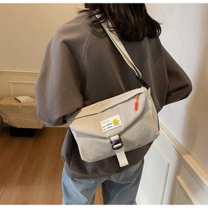 Detail der beige Umhängetasche mit TR-S Grafik und leuchtend orangem Reißverschluss
