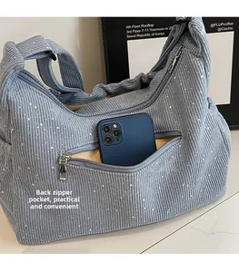 Detail of light blue corduroy tote with sequin finish showing a functional back zipper pocket
