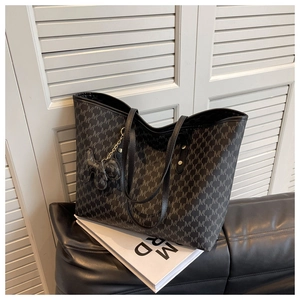 Detail of black monogram tote bag with MK pattern and cute bow charm accessory