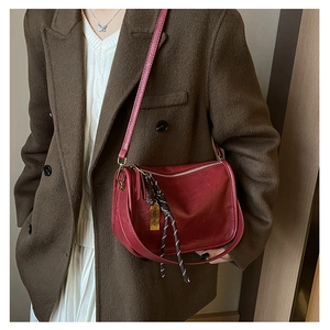 Détail du sac bandoulière en cuir rouge foncé avec finitions dorées et sangle tissée