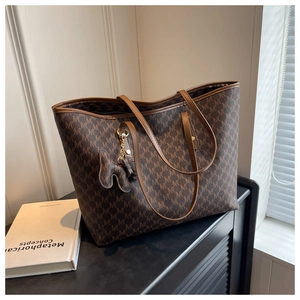 Detail of dark brown tote bag featuring M-letter pattern and elegant metal chain charm