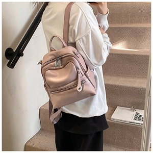 Close-up of pink faux leather backpack featuring multiple zip pockets and silver hardware