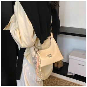 Détail d'un sac à bandoulière crème en similicuir avec logo et breloque de raquette
