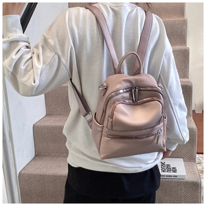 Pink litchi texture faux leather backpack featuring multiple zippered pockets on a model