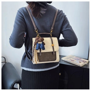 Detail of cream crocodile textured flap on a two-tone backpack with brown bear charm