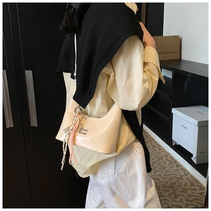 Détail d'un sac demi-lune crème avec pendentif décoratif en corde nouée de style chic