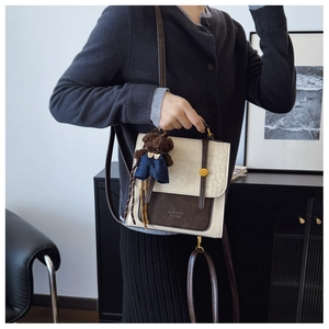 Detail of cream crocodile embossed mini backpack with brown trim and cute bear charm