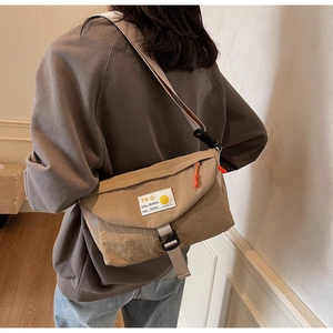 Seitenansicht der khakifarbenen Kuriertasche mit Schnalle und gelbem Smiley-Gesicht