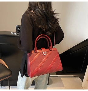 Vista dettagliata di una borsa in pelle rossa con trama a righe e manico rotondo