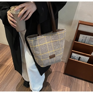 Détail d'un cabas vintage à carreaux avec des anses en cuir marron et texture tissée