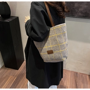 Detail of checkered tote bag with brown leather straps and black houndstooth pattern