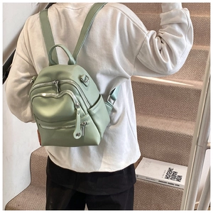Detailed side view of mint green mini faux leather backpack with metallic zippers