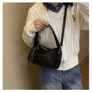 Détail du sac bandoulière cylindrique en cuir noir avec cordon rayé et bandoulière amovible