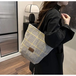 Detailed close-up of a large houndstooth woven tote bag worn on the shoulder by a model