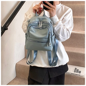 Detail view of light blue multi-zipper backpack with silver hardware and adjustable straps