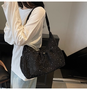 Detailed view of black nylon crossbody bag with white polka dots and drawstring pocket