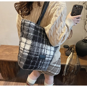 Detailed view of plush black and white checkered tote bag with black leather shoulder strap