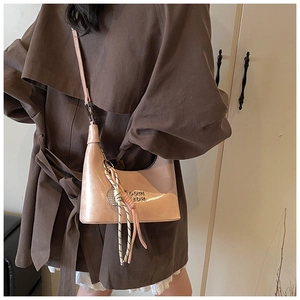 Détail du sac hobo avec finition brillante, logo en métal et breloque en corde tissée
