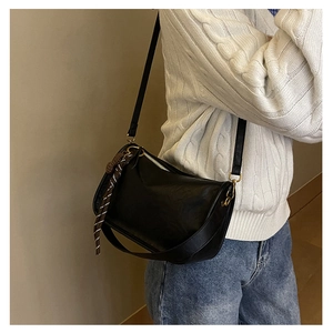 Détail d'un sac bandoulière demi-lune noir avec zip doré et cordon de style tressé
