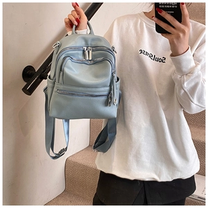 Detail of light blue mini backpack with pebbled leather texture and multi-zipper pockets