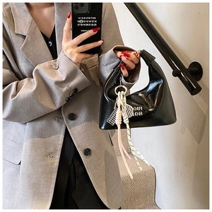 Détail du sac en cuir verni noir brillant avec poignée à nœud large et breloque argentée