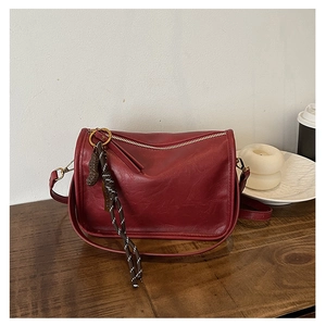 Détail du sac bandoulière en cuir rouge vin avec cordon de décoration tressé élégant