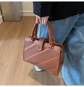 Dettagli della borsa marrone con fibbia a ferro di cavallo in metallo e strisce diagonali