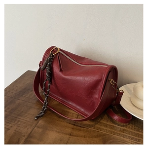Gros plan d'un sac à bandoulière cylindrique rouge foncé avec cordon tressé déco
