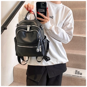 Detail of black pebbled leather backpack with silver zippers and dual front pockets