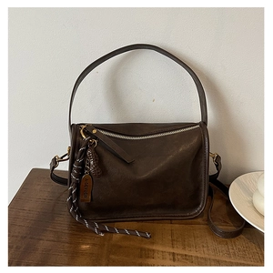 Détail du sac en similicuir marron foncé avec pendentif cacahuète et corde rayée